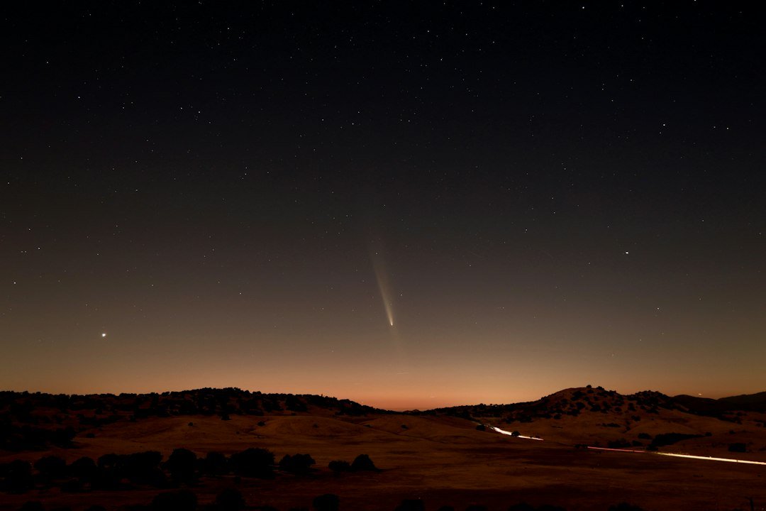 Photograph of comet C/2023 A3 Tsuchinshan–ATLAS in Earth's night sky; illustrative of comet impacts, not an image of the early Earth