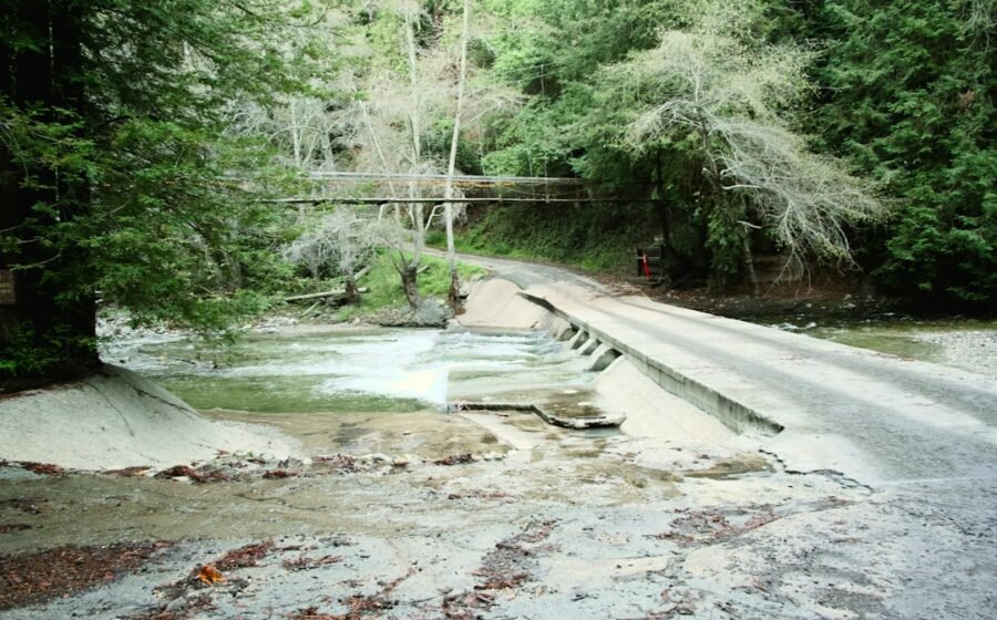 Illustrative image of a damaged bridge over a forested river, not a documentary photo of Hurricane Helene