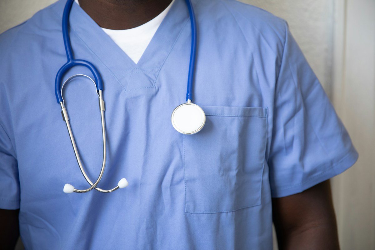 Clinician wearing blue scrubs and a stethoscope; illustrative contemporary medical image, not a portrait of a historical medical school graduate